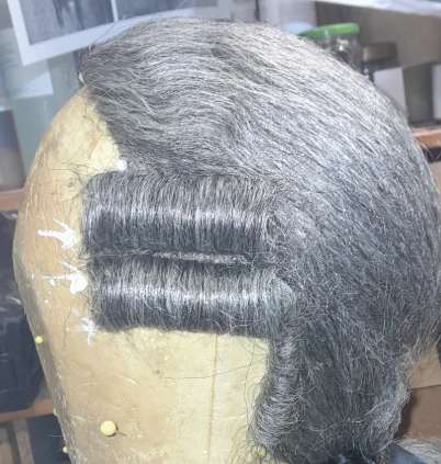 Grau melierte Perücke mit Locken auf Perückenkopf